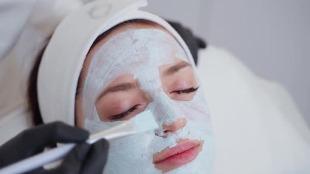 Lähikuva laukaus kosmetologi soveltamalla alginaatti naamio naisen kasvot kauneushoitola. Ihon puhdistus ja nuorentaminen - Materiaali, video