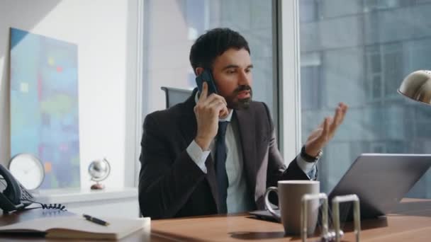 Verärgerter Unternehmer beschwert sich bei Telefonat im Büro. Besorgter bärtiger Manager diskutiert Arbeitsproblem am Smartphone. Nervöses Telefonat mit Laptop - Filmmaterial, Video