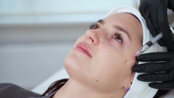 Zbliżenie na kobietę poddaną leczeniu twarzy w klinice medycyny estetycznej, która otrzymuje zastrzyki wypełniające skórę. Kosmetologia inwazyjna - Materiał filmowy, wideo