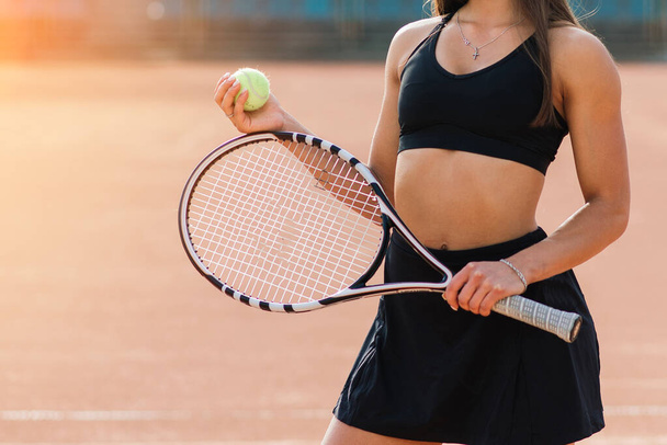 スポーツファッション。テニスコートの美しい女性。黒のトレンディーなスポーツウェアのスタイリッシュなセクシーな女の子の肖像屋外コートでテニスラケットを保持。高解像度. - 写真・画像