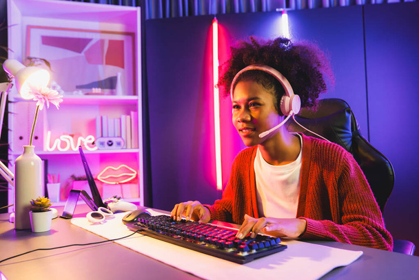 African American κορίτσι streamer παίζουν online καταπολέμηση με Esport εξειδικευμένη ομάδα φορώντας ακουστικά σε νέον χρώμα δωμάτιο φωτισμού. Μιλώντας άλλους παίκτες planing στρατηγικές για να κερδίσει τους ανταγωνιστές. Δοκιμαστής. - Φωτογραφία, εικόνα