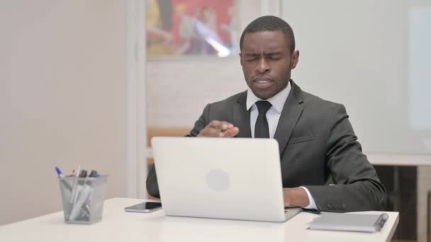 Homme d'affaires africain ayant mal à la tête tout en travaillant sur ordinateur portable dans le bureau - Séquence, vidéo