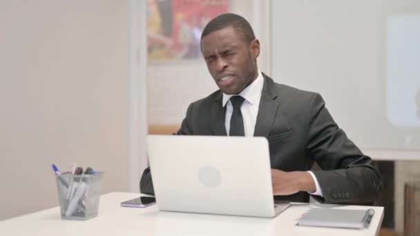 Empresario africano que tiene dolor de espalda mientras usa el ordenador portátil en la oficina - Metraje, vídeo