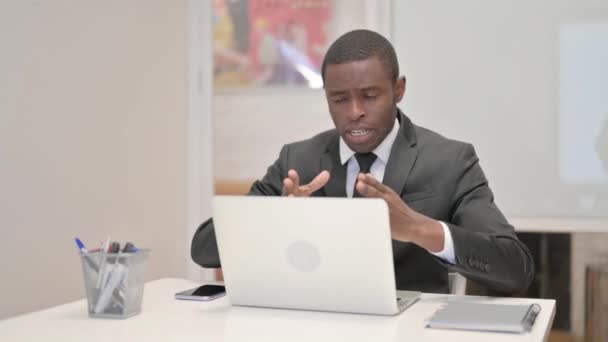Αφρικανός επιχειρηματίας Συνομιλία σε απευθείας σύνδεση στο φορητό υπολογιστή, ενώ κάθεται στο γραφείο - Πλάνα, βίντεο