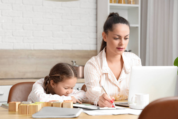 Lavorare madre con la sua figlioletta leggere libro in cucina - Foto, immagini