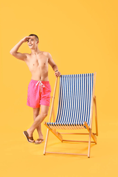 Teenage chlapec s palubou židle na žlutém pozadí - Fotografie, Obrázek