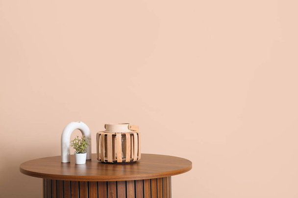 Ξύλινο τραπέζι σαλονιού με διακόσμηση κοντά σε μπεζ τοίχο - Φωτογραφία, εικόνα