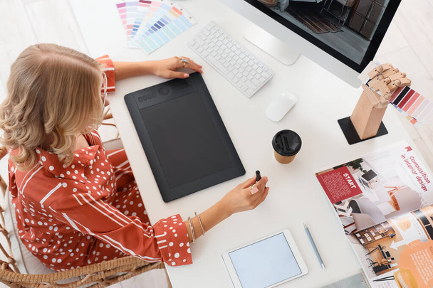 Vrouw interieur ontwerper werkt met grafische tablet aan tafel in kantoor, bovenaanzicht - Foto, afbeelding