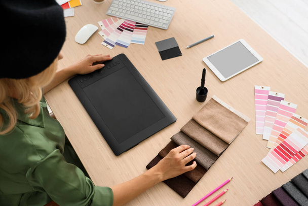 Женщина-дизайнер интерьера, работающая с образцами ткани за столом в офисе, вид сверху - Фото, изображение
