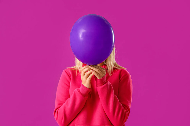 Schöne junge Frau in stylischem Kapuzenpulli mit Luftballon auf lila Hintergrund - Foto, Bild