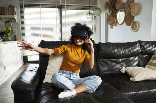 Weitwinkelaufnahme von Teenager-Mädchen in Virtual-Reality-Simulator, um Videospiel im Wohnzimmer zu spielen - Foto, Bild