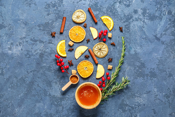 Ingredientes para preparar sabroso vino caliente con especias y un tazón de miel sobre fondo azul - Foto, imagen