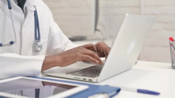 Primer plano del médico africano escribiendo en el ordenador portátil en el hospital - Imágenes, Vídeo