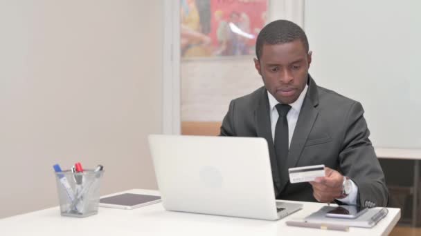 Empresario africano disfrutando de compras en línea en el ordenador portátil - Metraje, vídeo