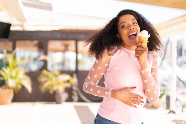 Jeune femme afro-américaine avec une crème glacée cornet à l'extérieur - Photo, image