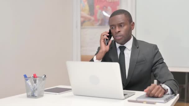 Afrikaans zakenman in gesprek over de telefoon op het werk - Video