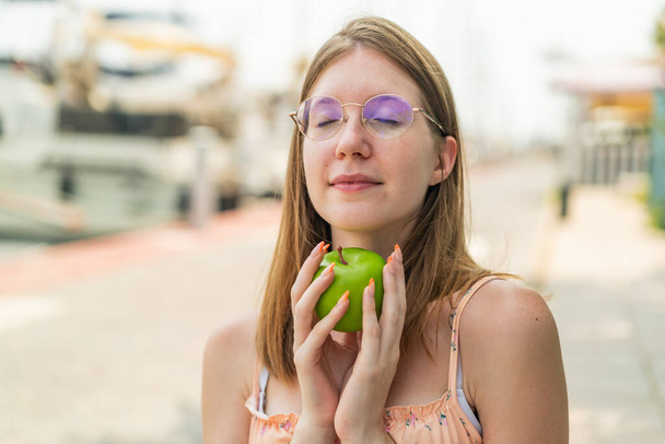 Joven francesa con gafas al aire libre sosteniendo una manzana - Foto, imagen