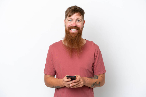 Punapää mies pitkä parta eristetty valkoisella taustalla lähettää viestin mobiili - Valokuva, kuva