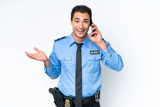 Junger kaukasischer Polizeimann isoliert auf weißem Hintergrund, der ein Gespräch mit dem Handy mit jemandem führt - Foto, Bild