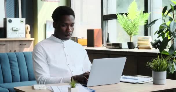 Przemyślany afro-amerykański przedsiębiorca efektywnie zarządza zadaniami w zaciszu domowego biura. Jego zaangażowanie w pracę jest oczywiste, ponieważ porusza się po obowiązkach zawodowych.. - Materiał filmowy, wideo