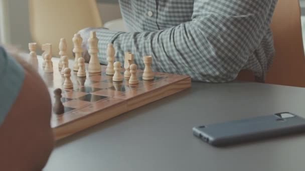 Tiro cortado de dois homens diversos irreconhecíveis jogando jogo de xadrez na mesa dentro de casa - Filmagem, Vídeo