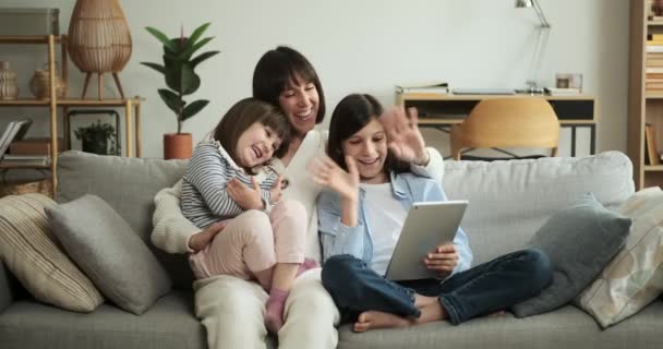 Familie houdt zich bezig met een videogesprek met behulp van een tablet in de woonkamer. Hun virtuele ontmoeting brengt geliefden bij elkaar en creëert een gevoel van saamhorigheid ondanks de fysieke afstand.. - Video