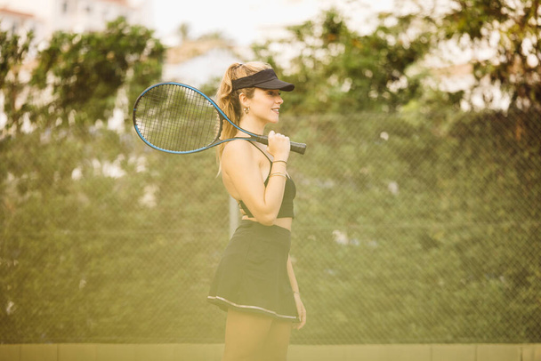 Portret młodej pięknej kobiety grającej w tenisa. Sportowiec dobrze się bawią grając w tenisa z przyjaciółmi. - Zdjęcie, obraz