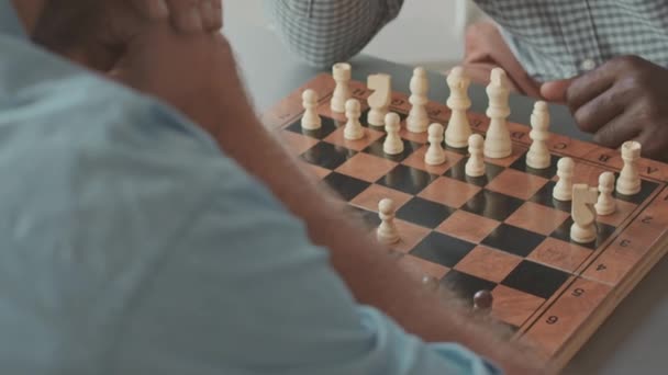 Обрізаний знімок двох невпізнаваних багатоетнічних чоловічих опонентів, які грають у шахи в приміщенні - Кадри, відео