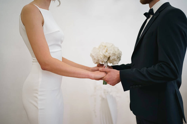 Podczas ceremonii ślubnej, panna młoda i pan młody trzymają się za ręce. Miłość i małżeństwo. - Zdjęcie, obraz