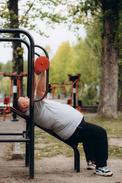 lihava mies laihduttaa harjoittelemalla urheilukentällä - Valokuva, kuva