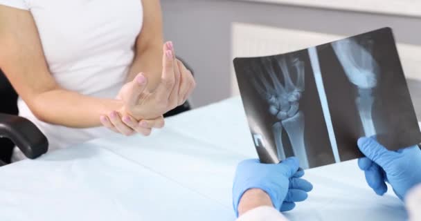 Lekarz reumatolog trzymając rentgen dłoni na tle chorego pacjenta 4k filmu. Diagnoza i leczenie koncepcji urazów dłoni - Materiał filmowy, wideo