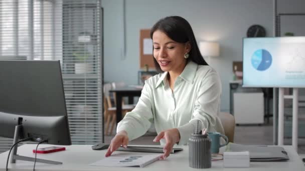 Modern ofisteki bilgisayarda çevrimiçi video konferansında ekibiyle finansal raporu tartışan genç bir çift ırklı iş kadını. - Video, Çekim