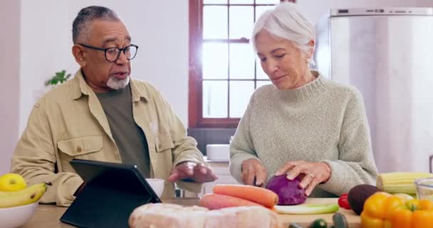 Cooking, talking or old couple with tablet or food for a healthy vegan diet together in retirement at home. Online, interracial or senior woman bonding in kitchen with an elderly man or dinner recipe. - Footage, Video