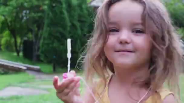 Lapsi puhaltaa kuplia takapihalla ulkona - Materiaali, video