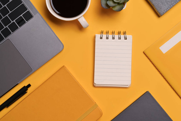 Ноутбук зверху, блокнот і чашка кави на жовтому фоні. Копіювати простір для вашого тексту. - Фото, зображення