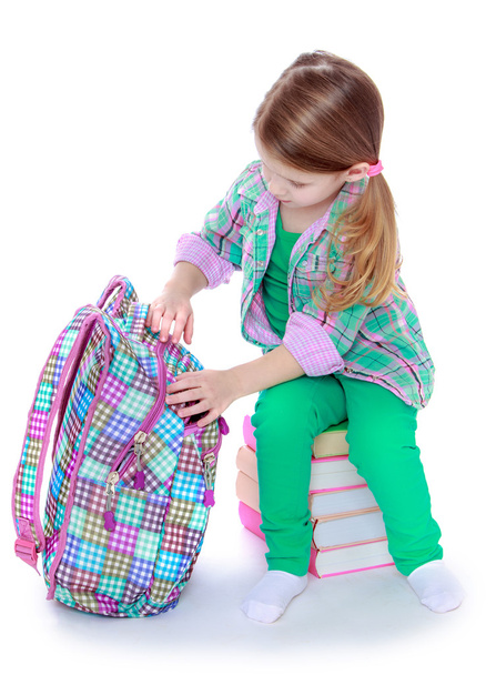 The girl opens a school backpack - 写真・画像