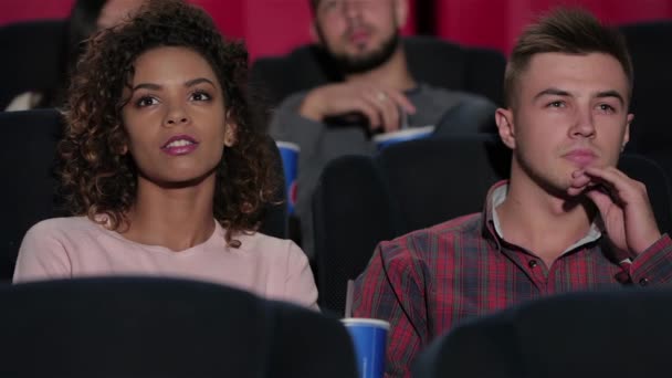 Young couple at the cinema. Cinema, entertainment and people concept - happy friends watching movie in theater. Couple and other people eating popcorn and drinking soda while watching movie at the - Footage, Video