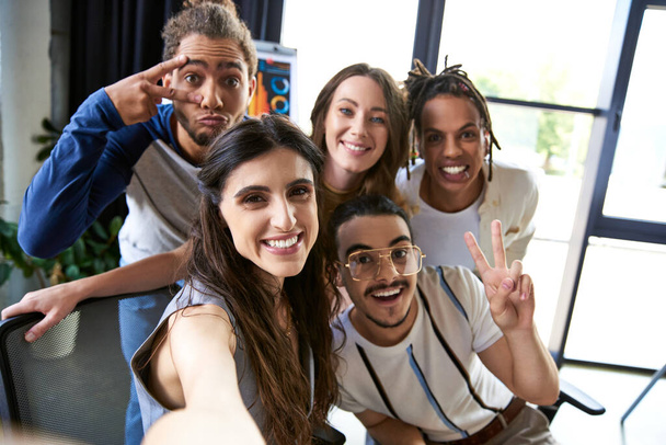 Porträt eines fröhlichen multiethnischen Teams, das in einem modernen Coworking-Büro gestikuliert und in die Kamera blickt - Foto, Bild