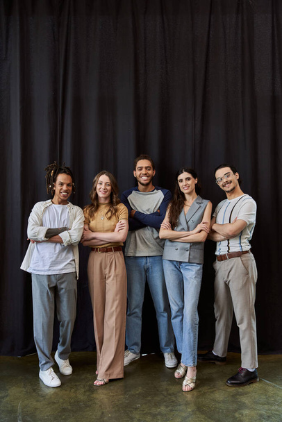 mosolygós multikulturális csapat elegáns alkalmi öltözék hajtogatott karokkal közel fekete függöny az irodában - Fotó, kép