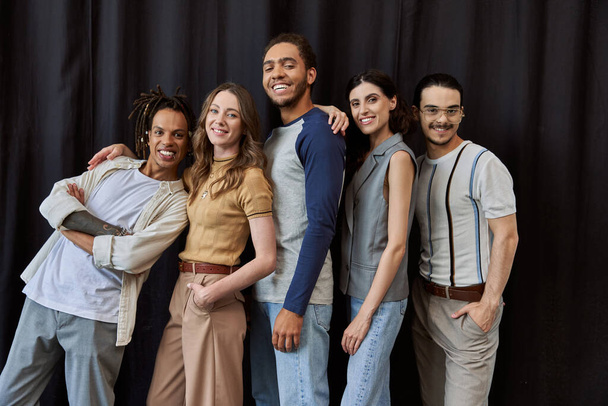 foto de grupo de equipe multiétnica bem sucedida sorrindo para a câmera no fundo preto no escritório moderno - Foto, Imagem