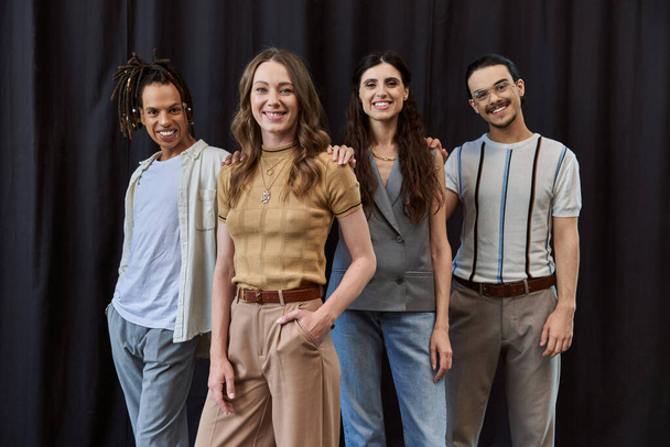 Gruppenfoto eines stilvollen multikulturellen Business-Teams, das in der Nähe eines schwarzen Vorhangs in die Kamera lächelt - Foto, Bild