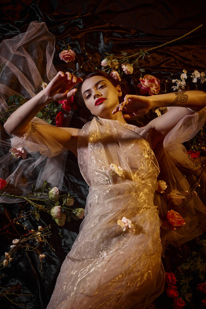 elegancia femenina, mujer sensual en vestido romántico transparente acostado entre hermosas flores - Foto, imagen