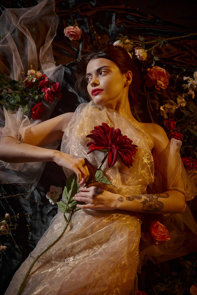 жіночна елегантність, брюнетка і романтична жінка в прозорому платті, що лежить серед красивих квітів - Фото, зображення