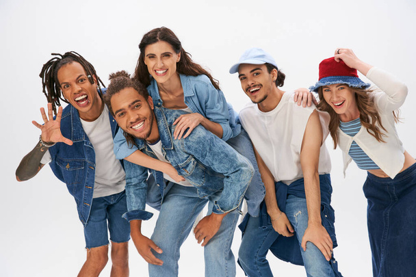 trendy african american man piggybacking woman near excited multiethnic friends having fun on grey - Photo, Image