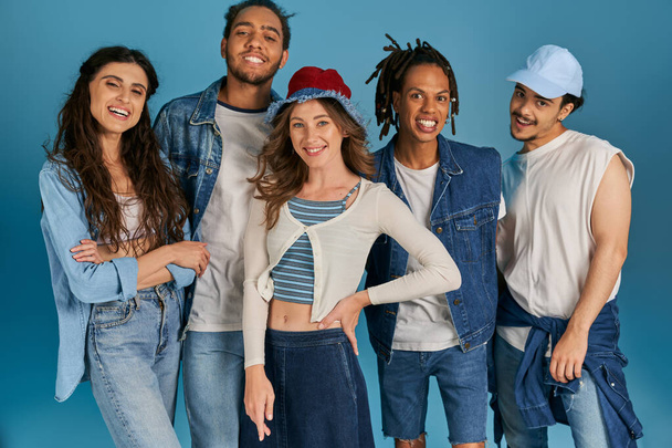 portrait de groupe d'amis interracial en tenue décontractée souriant à la caméra sur bleu, mode de rue - Photo, image