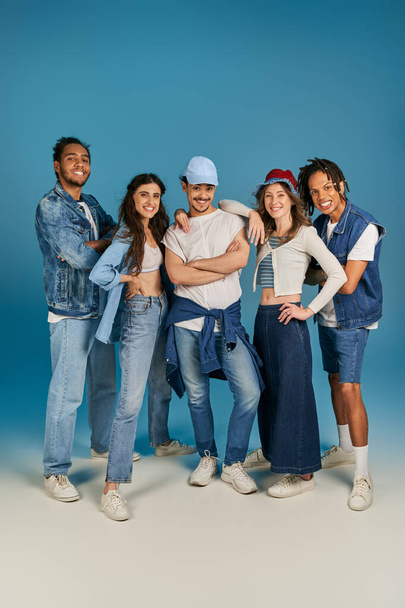 longitud completa de amigos interracial en ropa de moda y denim sobre fondo azul, agarre retrato - Foto, Imagen