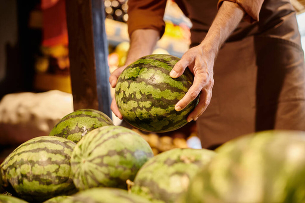 abgeschnittene Ansicht von reifen fröhlichen Verkäufer mit Bart Kommissionierung riesige frische Wassermelone im Lebensmittelgeschäft - Foto, Bild