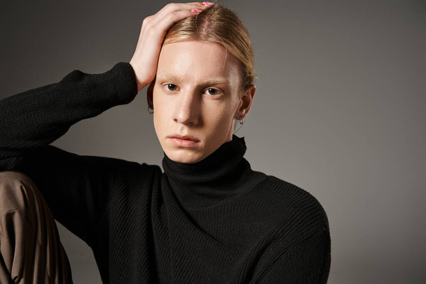 good looking non binary model in stylish black turtleneck posing and looking at camera, fashion - Photo, Image