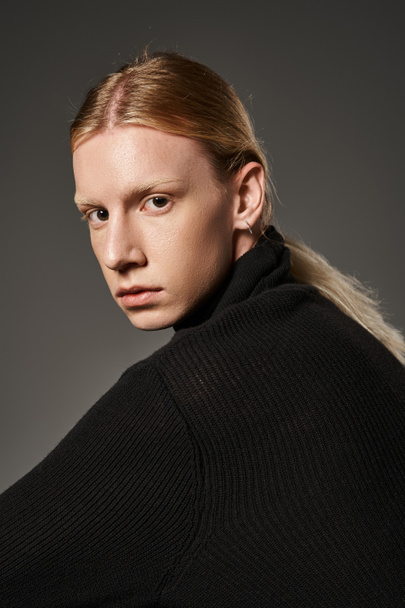 vertical shot of handsome non binary person with ponytail in stylish attire looking at camera - Photo, Image