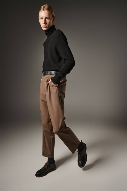 вертикальний знімок молодої небінарної моделі в чорному черепашку позує руками в кишенях, мода - Фото, зображення